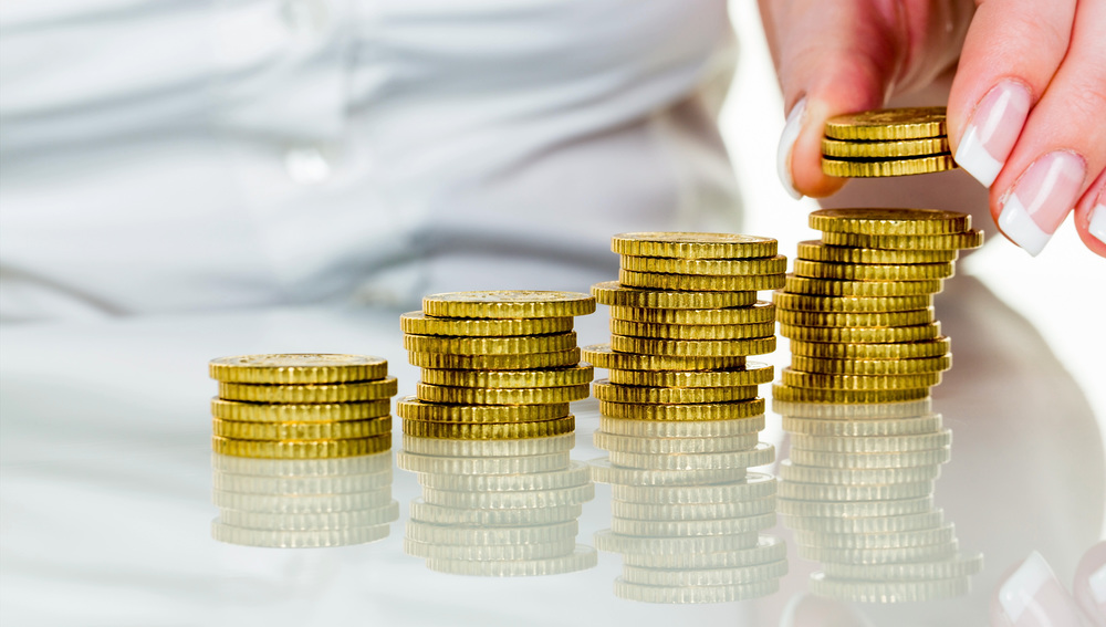 Eine Frau stapelt Münzen. Geld sparen für die Zukunft.