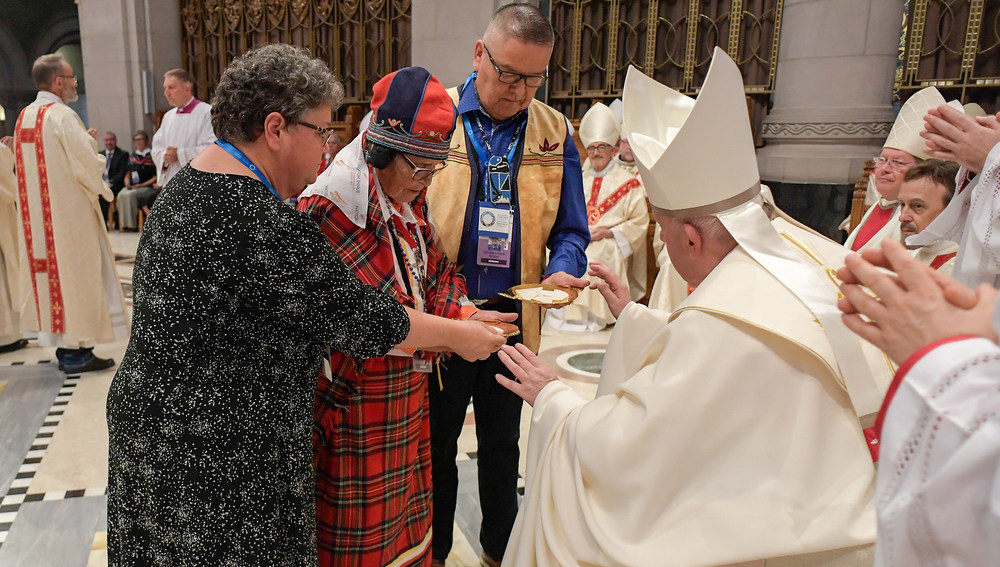 Papst Franziskus nimmt die Gaben entgegen von Vertretern der First Nations bei einer Messe im Wallfahrtsort Sainte-Anne-de-Beaupre (Kanada) am 28. Juli 2022. Im Vordergrund sitzen Bischöfe.