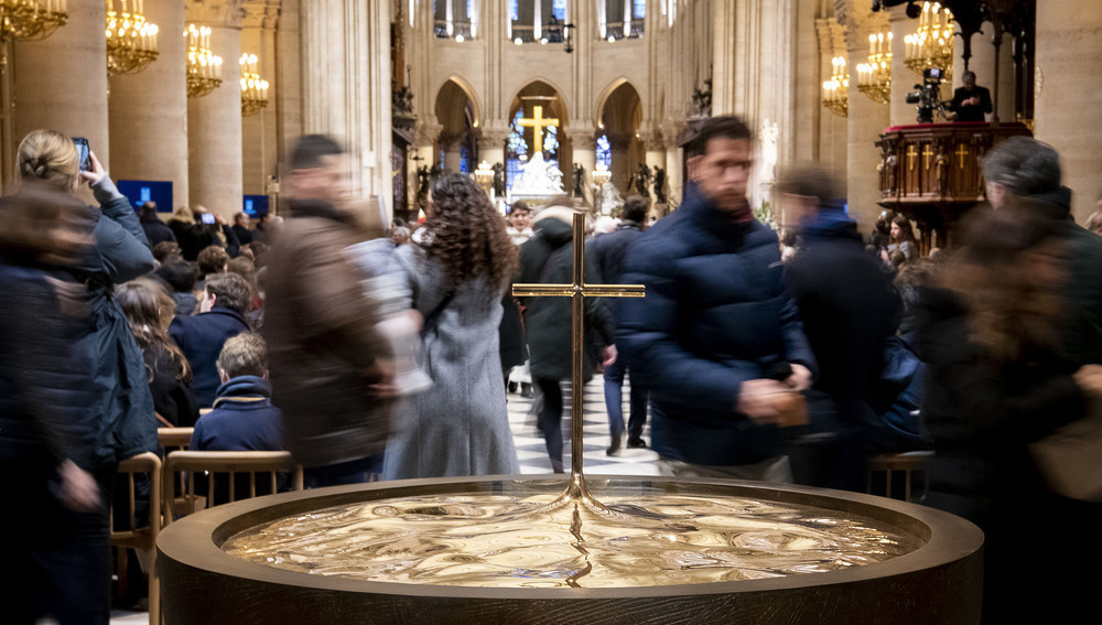 Gottesdienstteilnehmer beim Taufbecken der Kathedrale Notre-Dame