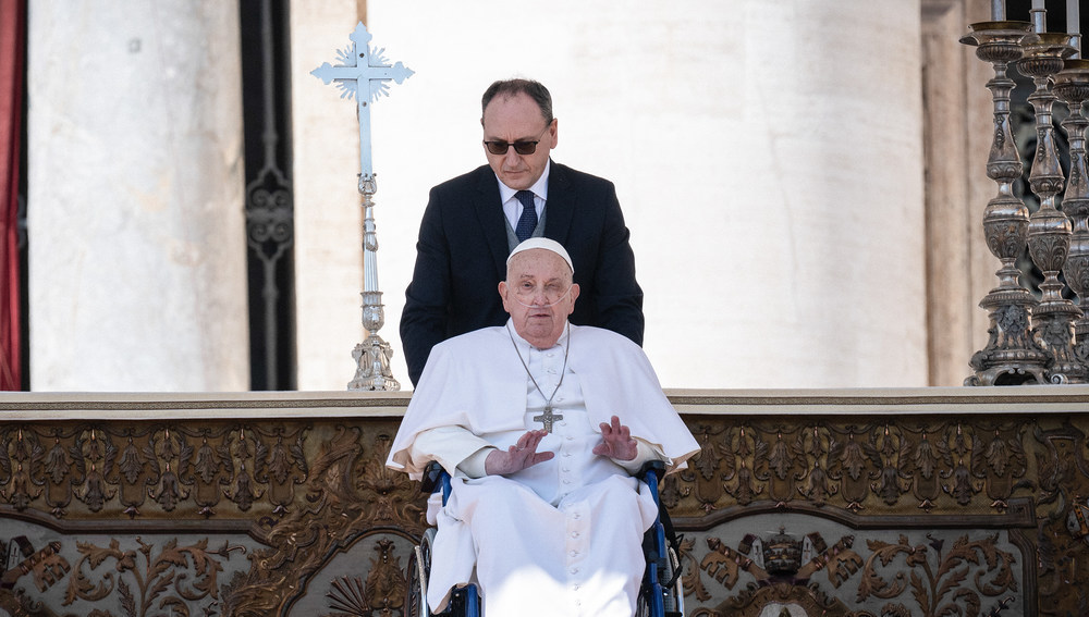 Papst Franziskus wird am 6. April 2025 von seinem persönlichen Krankenpfleger Massimiliano Strappetti im Rollstuhl auf den Petersplatz im Vatikan begleitet.